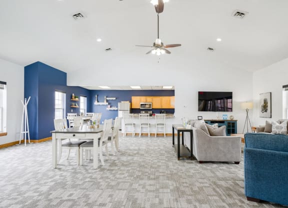Community clubhouse with couches and a dining room with a table and chairs with the kitchen in the back