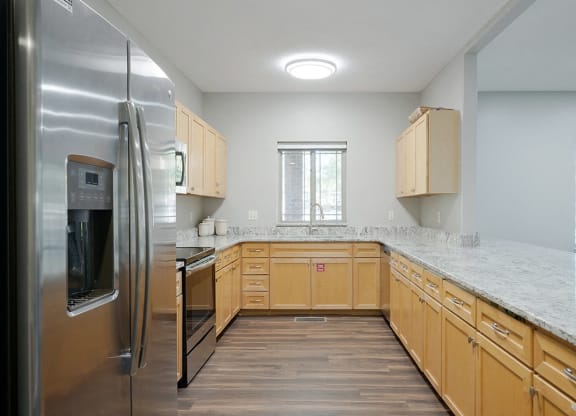 a kitchen with wooden cabinets and granite counter tops in the clubhouse