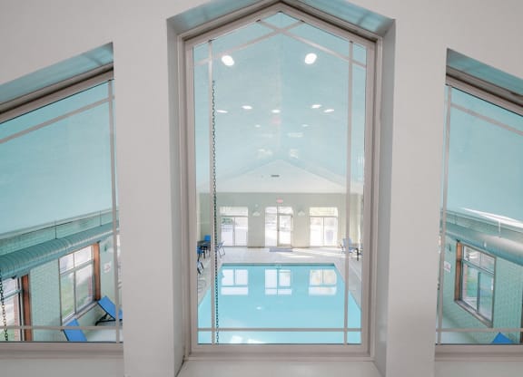 a three-pane angled window that overlooks an indoor pool