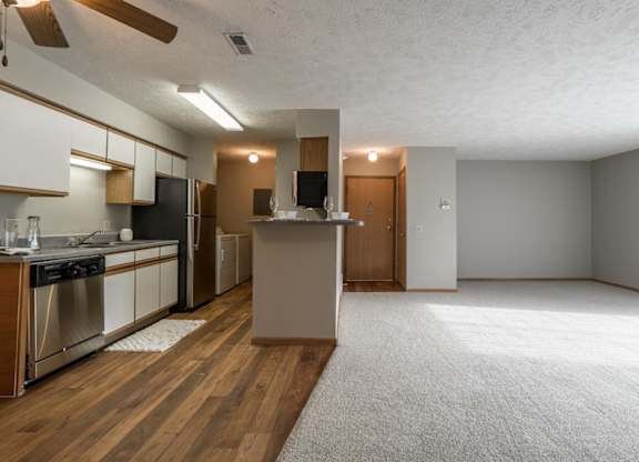 A kitchen with wooden floors that opens to living room