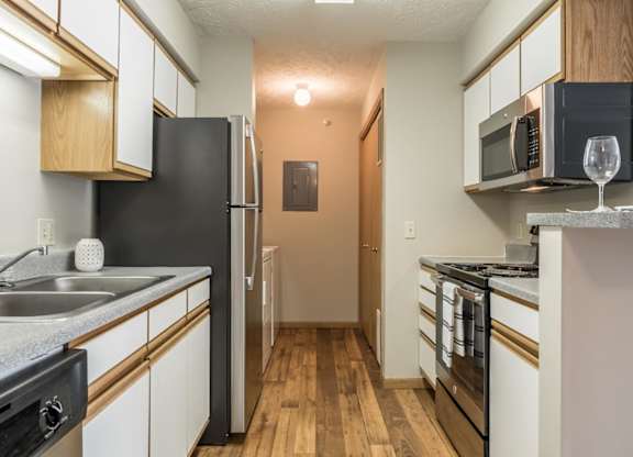 A kitchen with stainless steel appliances and white and oak cabinets.