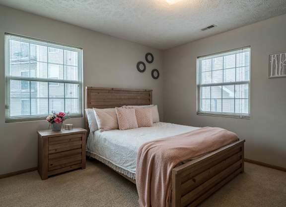 A bedroom with a bed, nightstand, and window.