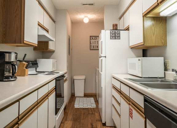 A kitchen with white appliances and white and oak cabinets.