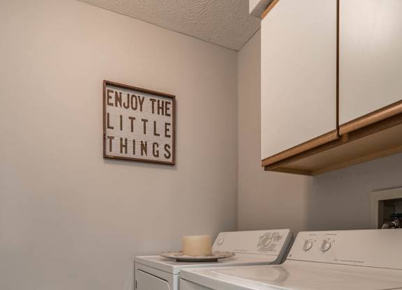 A laundry room with a washer and dryer and cabinet above them