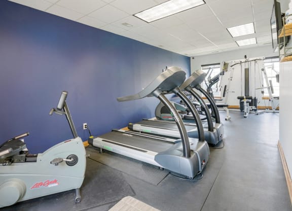 24-hour fitness center with a row of treadmills and other exercise equipment