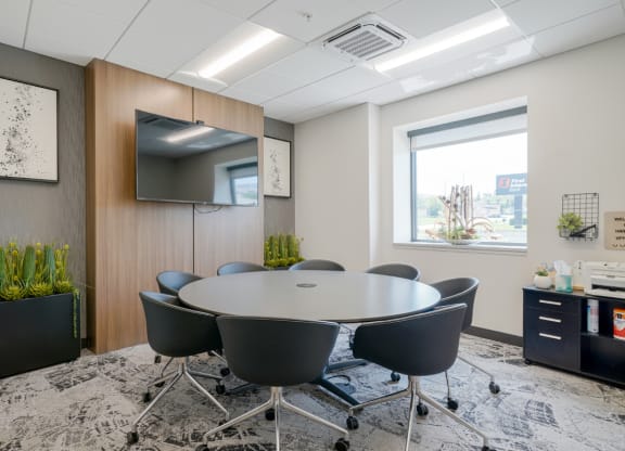 a conference room with a round table and chairs and a television
