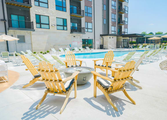 an outdoor pool with lounge chairs and a fire pit