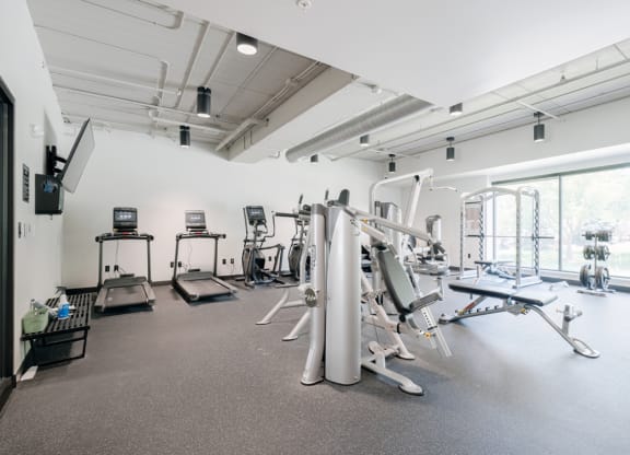 a gym with various exercise equipment in a room with windows