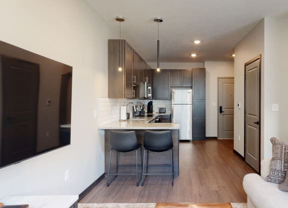 a kitchen a with two bar stools at the counter