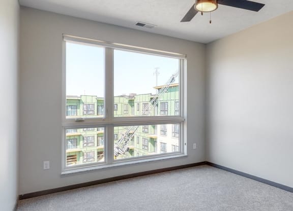 Bedroom with large window and ceiling fan in the Melody floor plan at Haven at Uptown in Lincoln, NE