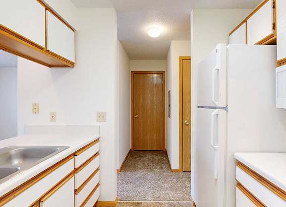 A galley kitchen with white appliances and wooden cabinets