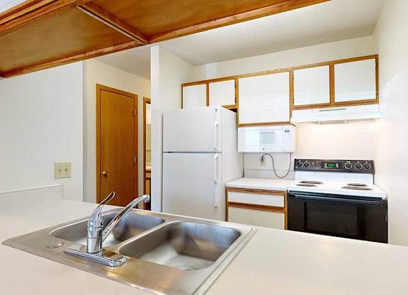 Kitchen with white appliances, white and wooden cabinetry, and a double basin sink