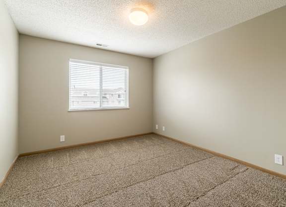 a bedroom with a carpeted floor and a window with blinds