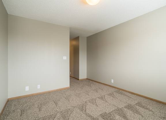 a bedroom with a carpeted floor and a hallway to the attached bathroom