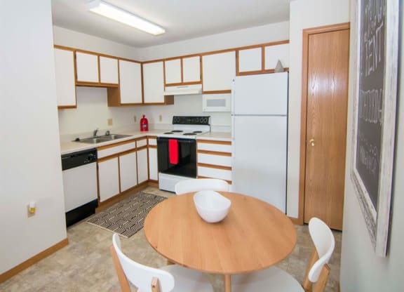 L-shaped kitchen with white cabinets and small dining area