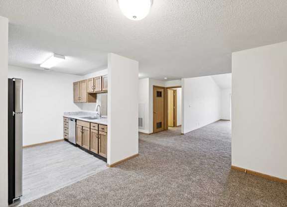 A kitchen area with a sink, cabinets, and a refrigerator.