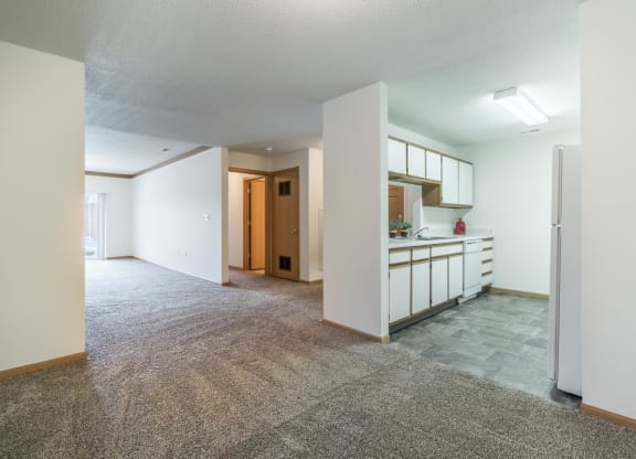 an empty living room and kitchen with a refrigerator