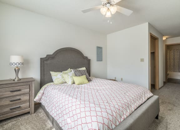 Master bedroom with ceiling fan and attached bathroom at Northridge Heights in Lincoln