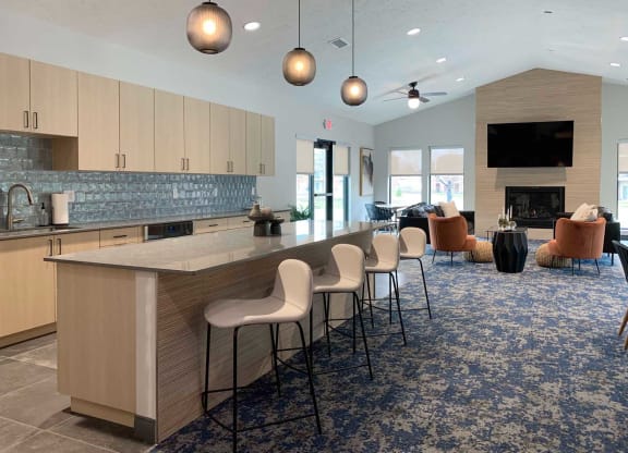 a large kitchen with a bar and a clubhouse community room with a fireplace