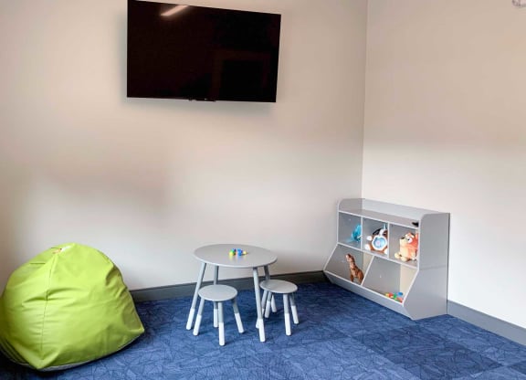 a children's area within the fitness center with a table and chairs and a television