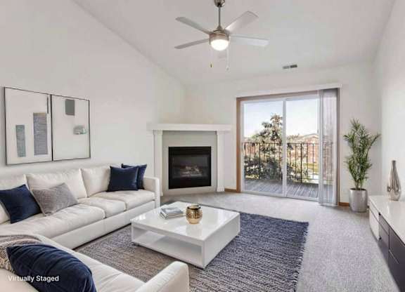 A living room with a white couch, a fireplace, and a ceiling fan.