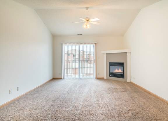 an empty living room with a fireplace and a window