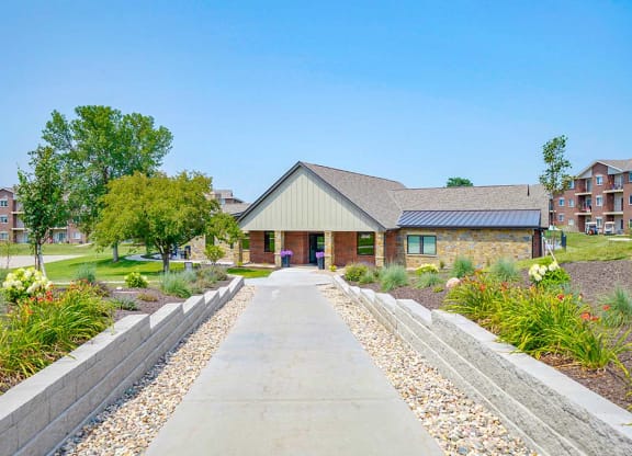 Walkway leading to a clubhouse with trees and landscaping