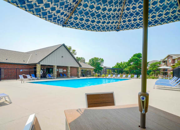 Swimming pool with an umbrella-covered table and chairs in the foreground
