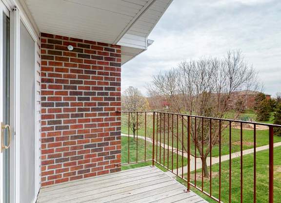A balcony with a brick wall and a metal railing.