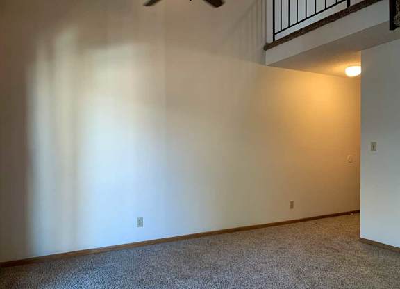 a living room with a vaulted ceiling, ceiling fan, and a loft area above