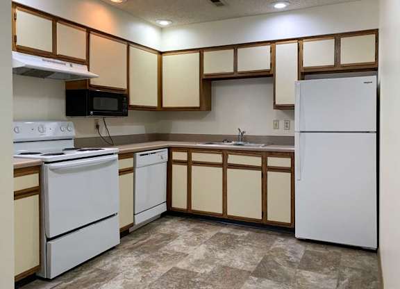 a kitchen with white appliances and white and wooden cabinets