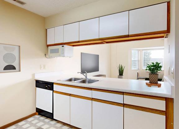 A kitchen with a white counter, white cabinets, and a pass through to the living room.