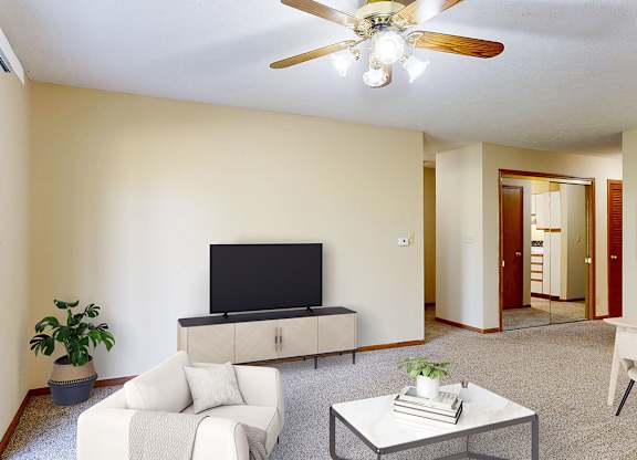 A living room with a television, a white couch, and a coffee table.