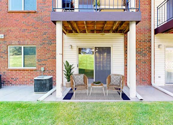 A patio with a table and chairs is surrounded by a brick building.