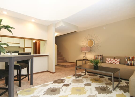 Loft style apartment living room looking into kitchen area with stairs off of the living room