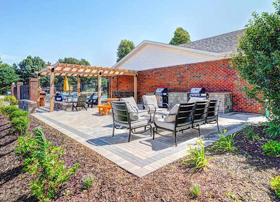 An outdoor patio with social seating areas, a picnic table, grilling stations, a fire pit, and a pergola.