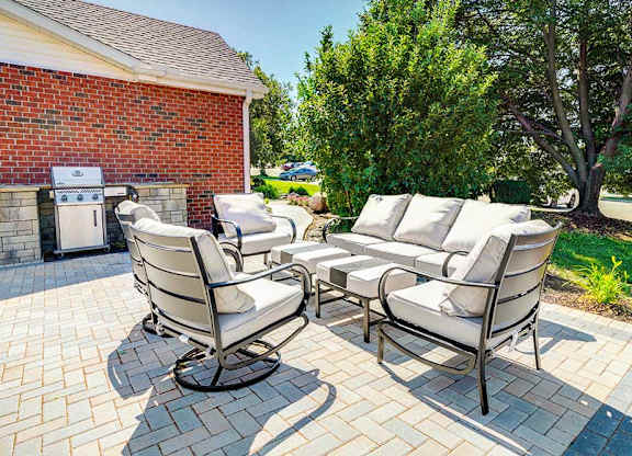 A patio with a set of white cushion chairs and a table, great for outdoor social gatherings.
