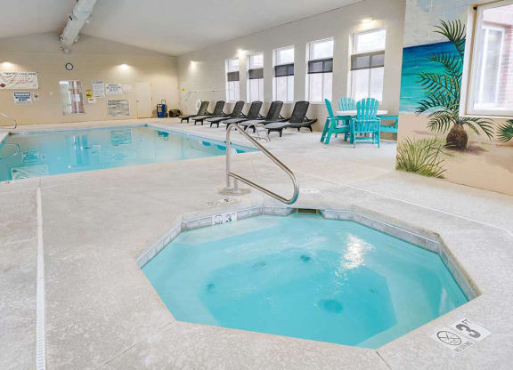 an indoor pool and hot tub with lounge chairs chairs