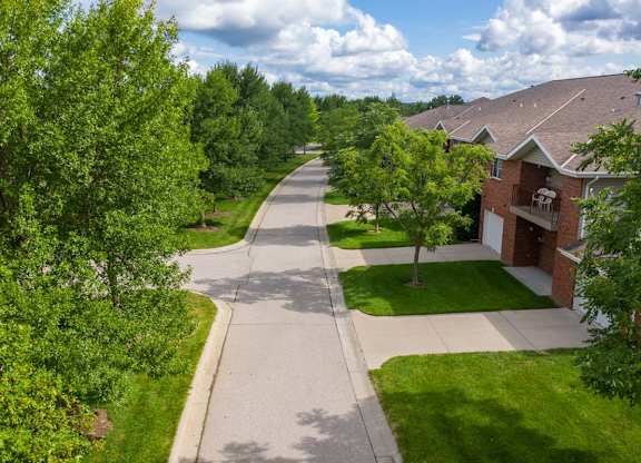 A residential street with houses on both sides and trees lining the road.