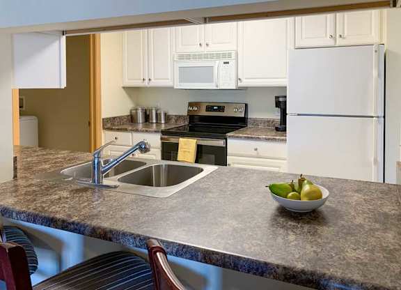 a kitchen with a bar top style counter, a sink, stove, and refrigerator