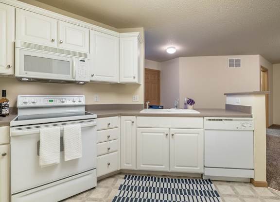 A kitchen with white appliances and cabinets.