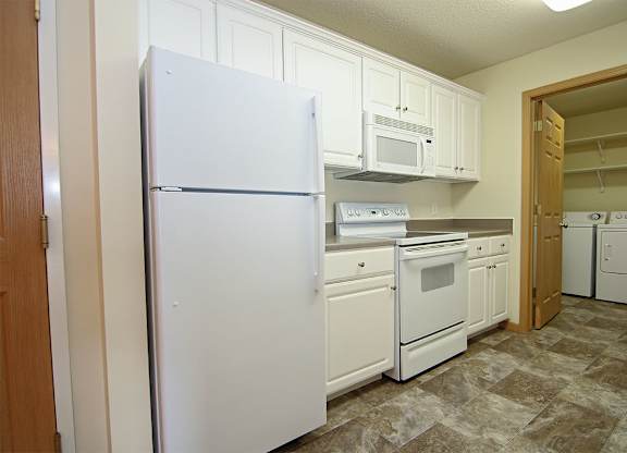 A kitchen with white appliances and cabinets.