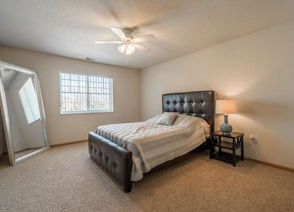 A bedroom with a bed, a nightstand, and a ceiling fan.
