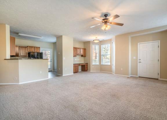 An open living room with a built-in desk next to a spacious kitchen.