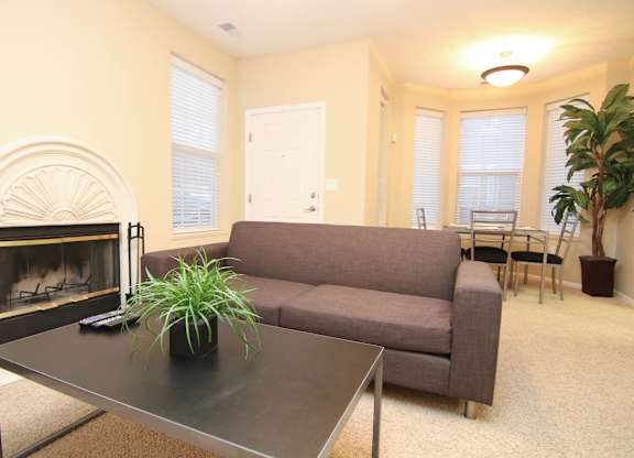 A living room with a grey couch, a fireplace, and lots of windows