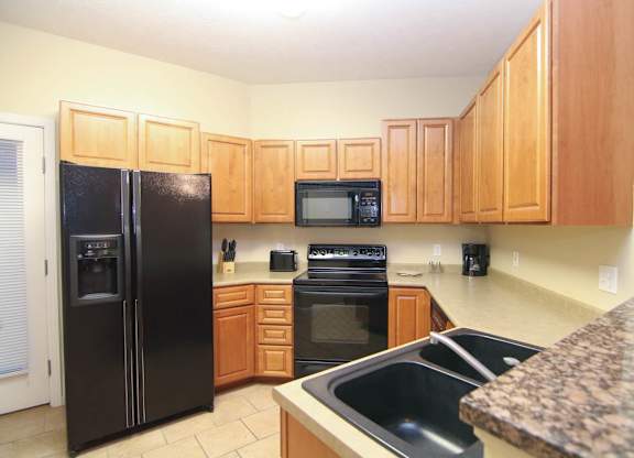 A kitchen with brown cabinets and black appliances.