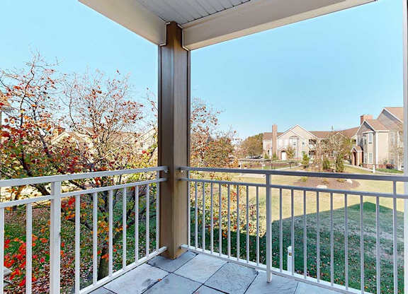 a private balcony with a view of surrounding buildings and greenery