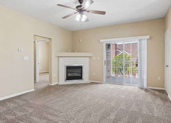 Apartment living room with carpet, fireplace, ceiling fan, and sliding glass doors leading to a balcony.
