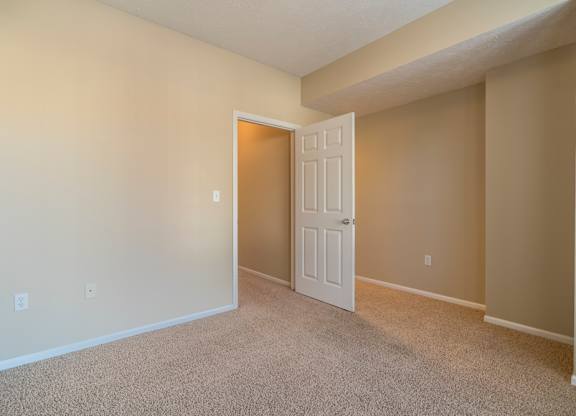 A bedroom with a white door and carpeted floor.