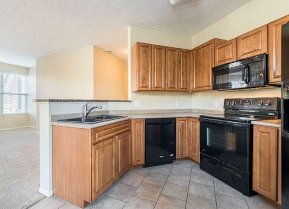 A kitchen with black appliances and wooden cabinets.